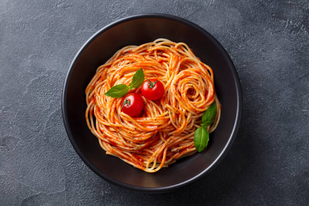 makaron, spaghetti z sosem pomidorowym w czarnej misce. tło łupków. widok z góry. - cherry tomato tomato sauce isolated close up zdjęcia i obrazy z banku zdjęć