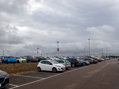 Luton, UK. This is the long stay car park at Luton Airport with a full lane of cars all parked whilst their owners have flown overseas.