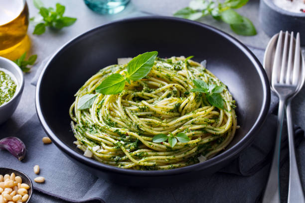 pasta spaghetti mit pestosauce und frischen basilikumblättern in schwarzer schüssel. grauer hintergrund. nahaufnahme. - close up green plate salad stock-fotos und bilder