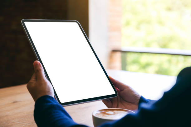 istock a woman holding black tablet pc with blank white screen with coffee cup on wooden table 1188645709