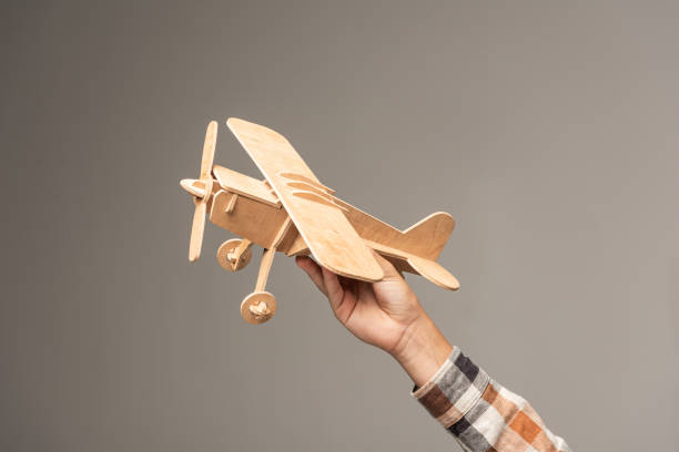 cropped view of boy holding wooden toy plane isolated on grey cropped view of boy holding wooden toy plane isolated on grey toy airplane stock pictures, royalty-free photos & images
