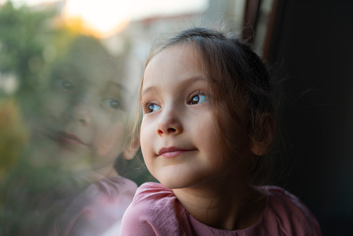 Little girl looking through window.