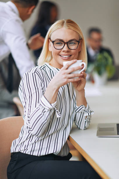 istock Smiling young businesswoman sitting at work drinking a coffee 1188648945