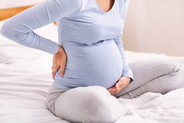 istock Pregnant Lady Having Backache Sitting On Bed In Bedroom, Cropped 1188649974