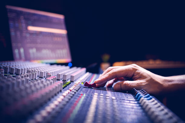 male producer, sound engineer hands working on audio mixing console in broadcasting, recording studio stock photo