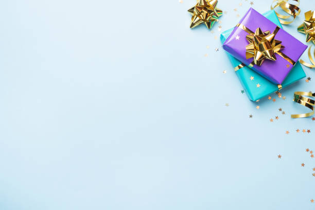 płaskie tło świeckie dla obchodów bożego narodzenia i nowego roku. pudełka na prezenty są fioletowe i turkusowe ze złotymi wstążkami i gwiazdkami konfetti na niebieskim tle. spacja na kopiowanie z góry. - gift purple turquoise box zdjęcia i obrazy z banku zdjęć