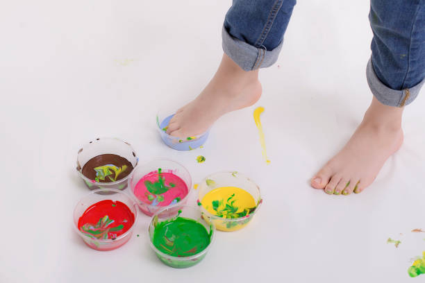 istock Kid in jeans getting his foot wet with blue color paint 1188663309