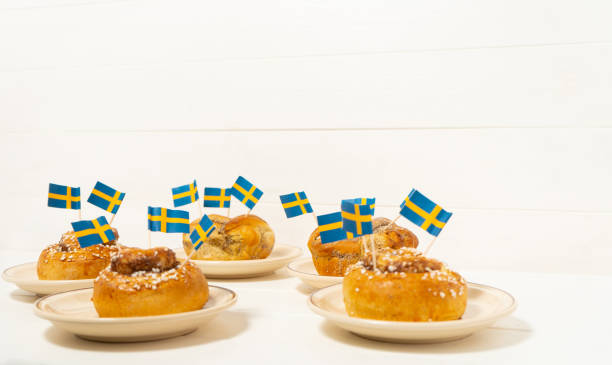 istock Swedish cinnamon buns (kanelbullar) on the white wooden table. Swedish flags. Coffee break (fika) 1188663679