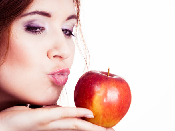 istock Woman holds apple fruit close to face, isolated 1188663873