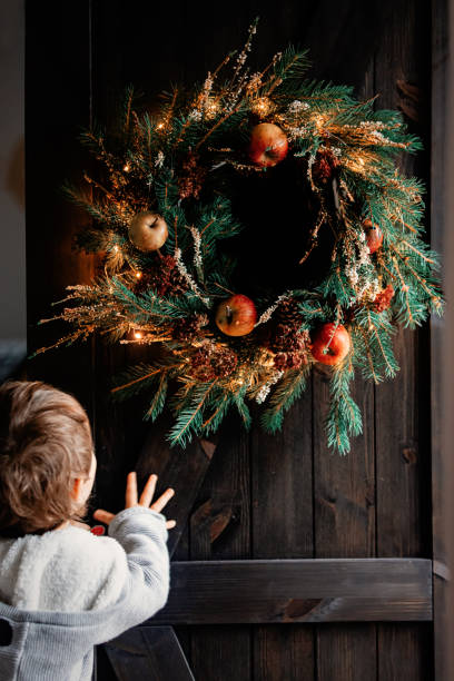 istock boy and handmade Christmas wreath on a door 1188665236