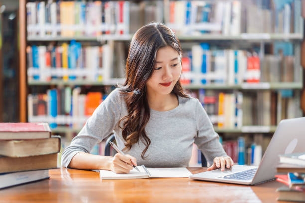 Asian young Student doing homework in library of university stock photo