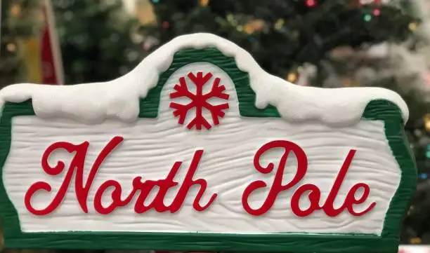 Close view of decorative North Pole Sign with Christmas tree visible in the background - Christmas holiday decoration