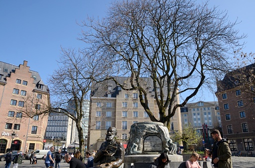 Brussels, Belgium - March 29, 2019: People sitting at sculptural bronze bench in the old town of Brussels, Belgium.