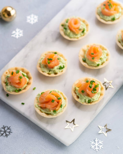 istock Canapes with smoked salmon, cream cheese and avocado on light background with space for text. Christmas and new year holidays background concept. Starters snacks recipe ideas. Top view. 1188683905