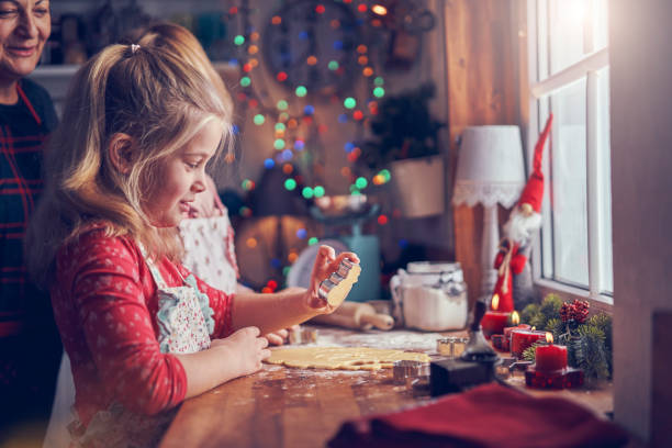 쿠키 커터로 크리스마스 쿠키를 준비하는 어린 소녀 - pastry cutter family holiday child 뉴스 사진 이미지