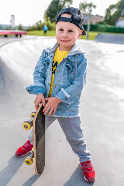 istock Cheerful little boy 3-5 years old. Happy smiling stands with skateboard. Training learning ride skateboard. Autumn day summer city. Concept of motivation of children for sports and fitness. 1188686313