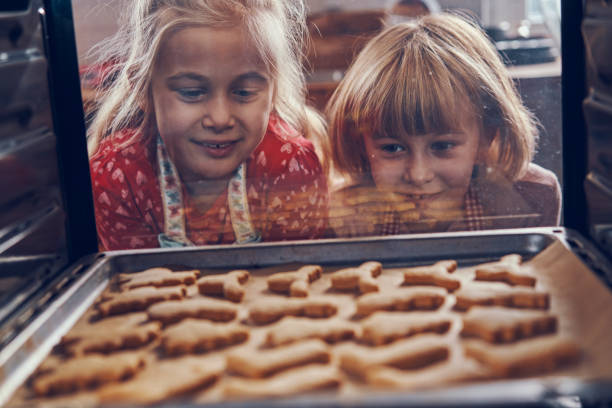little girls baking christmas cookies in the oven - pastry cutter family holiday child imagens e fotografias de stock