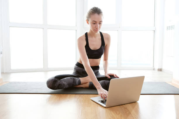 istock Woman using laptop while sitting on yoga mat 1188690334