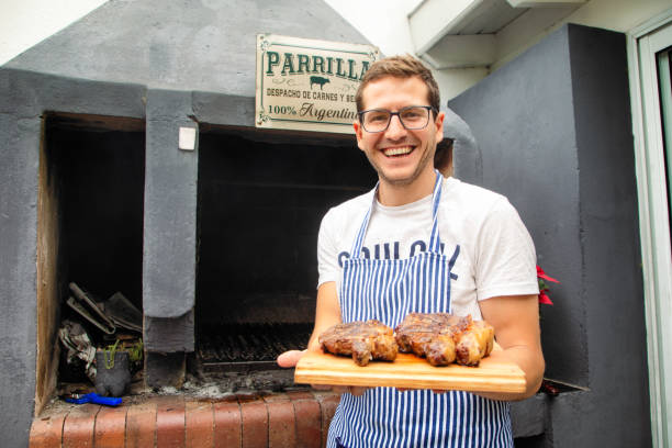 Millennial Argentinian cook presenting roasted rib eye and strip steaks