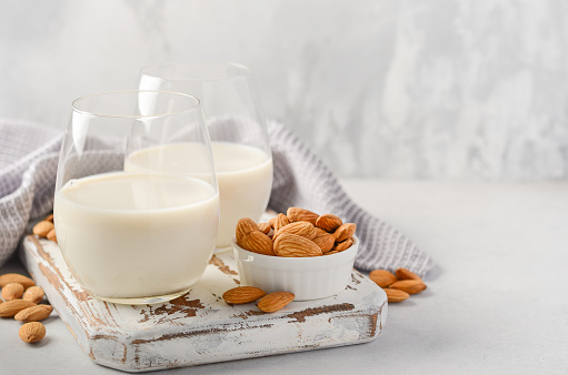 Almond milk and almonds on a white wooden cutting board, selective focus.
