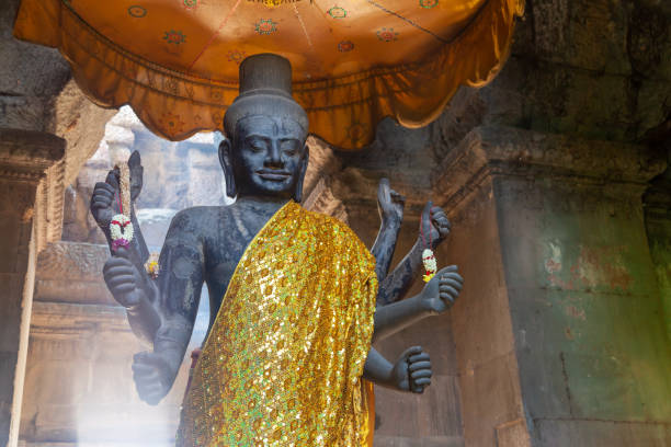 statue von vishnu in angkor wat. stehend an einem schönen ort, der von hinten von der sonne beleuchtet wird, die durch ein opeing in der decke scheint. - khmer stock-fotos und bilder