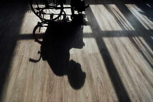 Silhouette on floor of man sitting on wheelchair