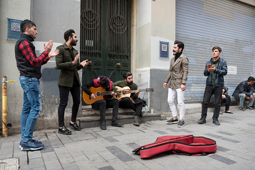 Istanbul, Turkey - November 10, 2017: Musicians play guitar, clap, and sing, busking on stiklal Avenue in the Taksim area of Istanbul.