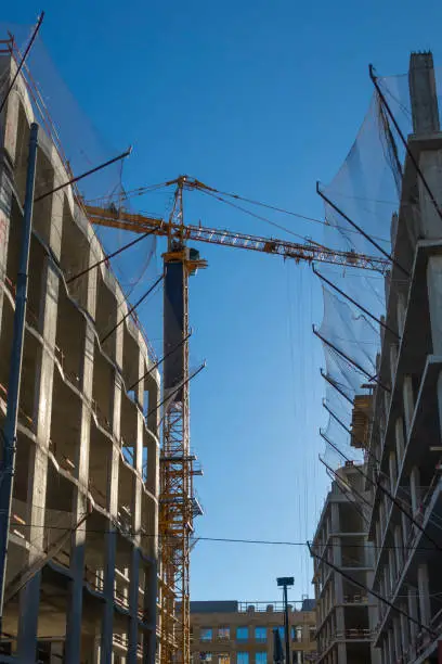 Building complex construction site. Yellow crane against blue sky.