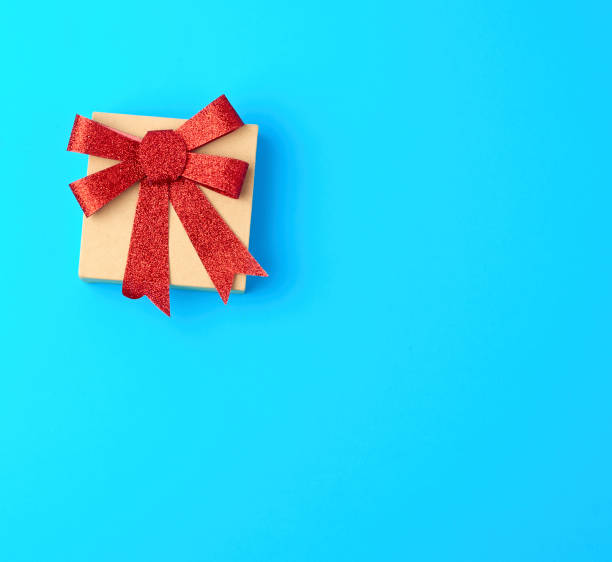 istock closed brown gift box with a red shiny bow on a blue background 1188703345