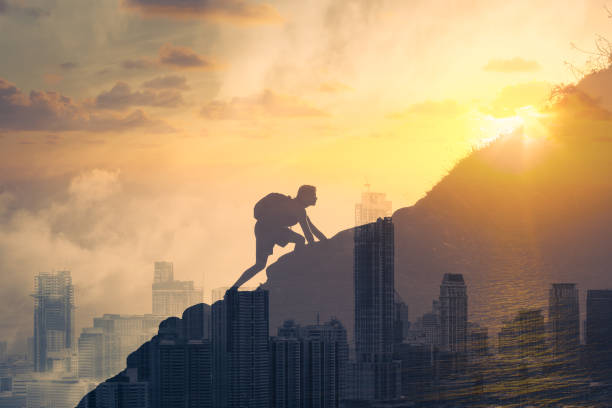 Young determined man climbing up mountain overlooking the city. People, power, challenging yourself, never giving up, and hard work concept. Double exposure clambering stock pictures, royalty-free photos & images