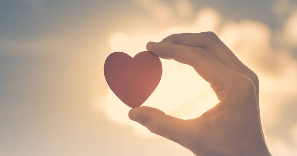istock Hand holding heart against sunset sky. 1188704250