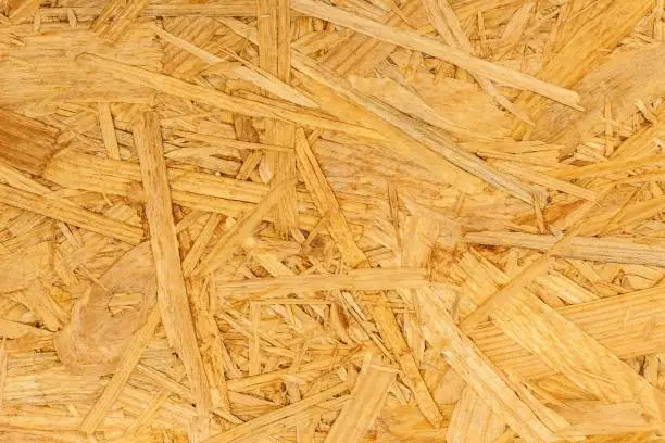 Building material. OSB boards are made of brown wood chips sanded into a wooden background. Background from wood fiber board.