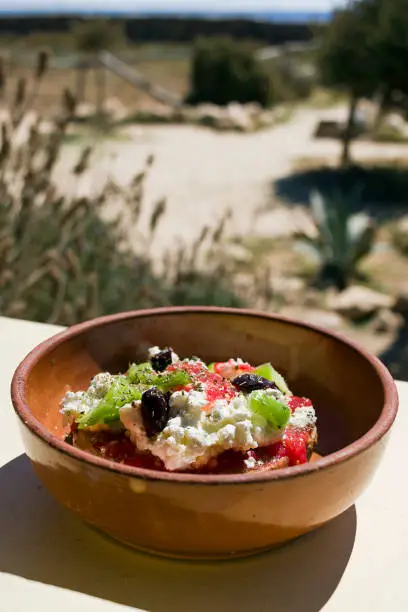 Dakos is one of the dishes most recognized with Cretan cuisine.Slice of soaked dried bread or barley rusk topped with chopped tomatoes,  cheese and capers or olives.