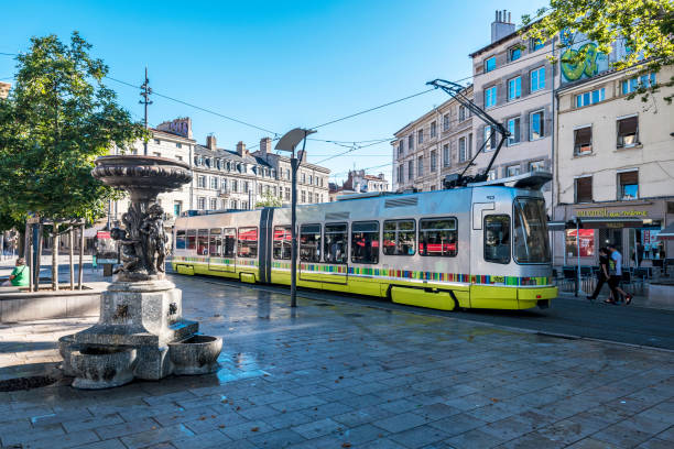 Street view in Saint Etienne downtown. The tramway passing along the square Place du Peuple. The Statue with fountain is at foreground. Saint-Etienne, France - July 29, 2019 Street view in Saint Etienne downtown. The tramway passing along the square Place du Peuple. The Statue with fountain is at foreground. saint étienne photos stock pictures, royalty-free photos & images