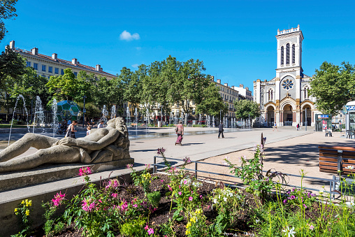 Saint-Etienne, France - July 29, 2019 The square of Jean Jaures in Saint Etienne downtown with fountains. Morini Andre catholic church is at right background.