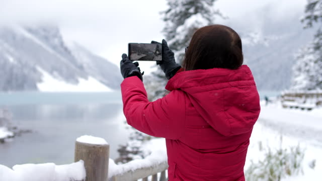 Woman taking a photo of  winter lake louise