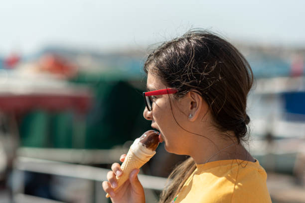 грусть девушка ест вкусное мороженое - child looking messy urban scene стоковые фото и изображения