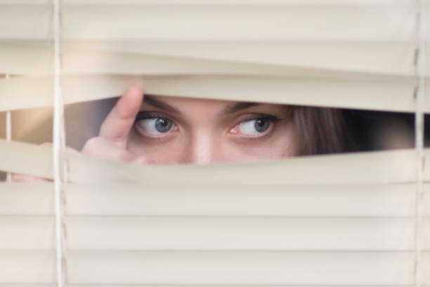 istock girl peeps out through the blinds 1188728779
