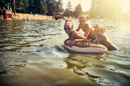 Kids are splashing and having fun on swim ring floating on the lake. Kids are laughing and having fun.
Nikon D810