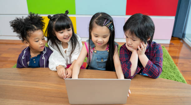 gruppe von kleinen kindern vielfalt sehen film zusammen auf laptop. kinder spielen mit laptop-computer zu hause - child asian ethnicity little girls toddler stock-fotos und bilder