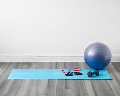 Detail from a living room of a modern house with yoga mat and plates ball