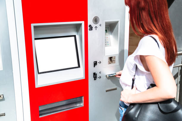 istock Young redhead woman inserts banknote into terminal 1188738586