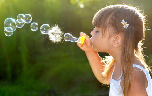 Little girl playing with bubble wand