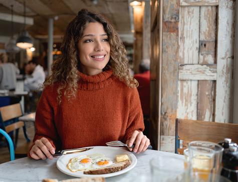 Portrait of a happy woman having breakfast at a cafe in London - food and drinks concepts