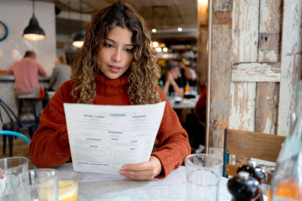 femme à un restaurant affichant le menu - menu photos et images de collection