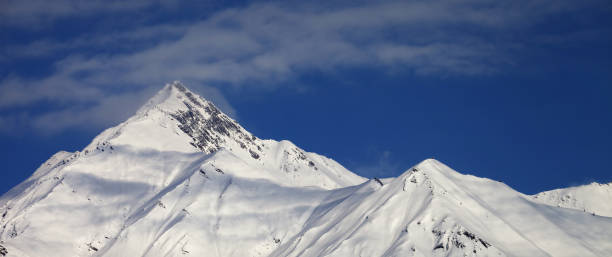 istock Snowy slope and blue sky with clouds at sunny winter day 1188759815