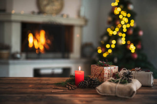 Beautiful Christmas decoration at home, fireplace with tree and focus on foreground candle with wrapped gifts.