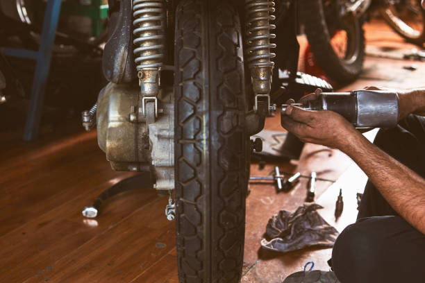 Mechanic repairing motor bike, small workplace