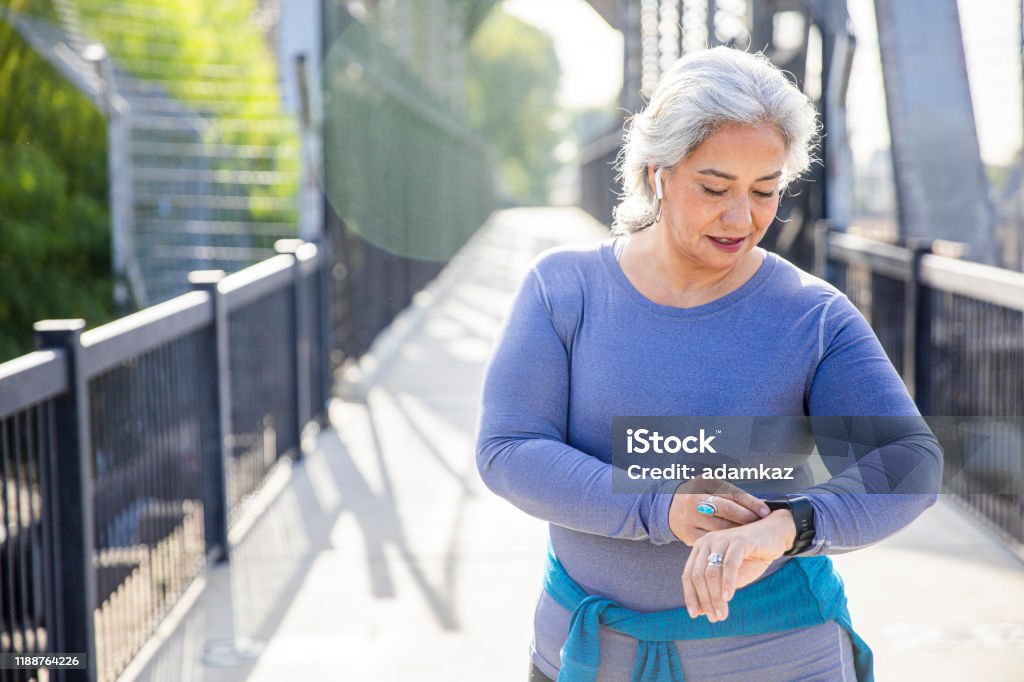 Mature Mexican Woman using fitness tracker A mexican woman checking her fitness tracker Fitness Tracker Stock Photo