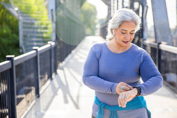 Mature Mexican Woman using fitness tracker A mexican woman checking her fitness tracker fitness tracker stock pictures, royalty-free photos & images